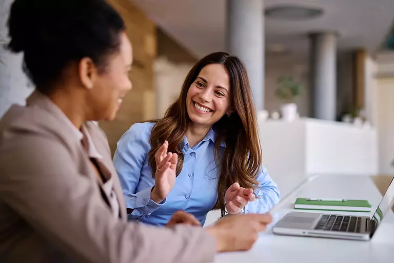 Two women having a discussion in front of a laptop.