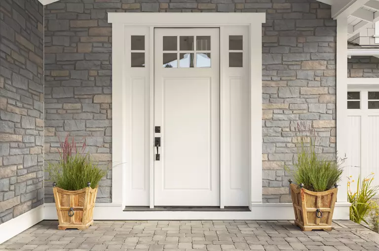 A home‘s white front door and a stone veneer. 