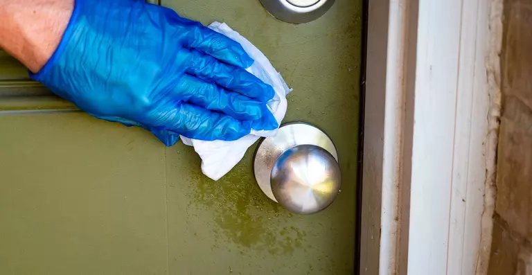 A homeowner cleaning their fiberglass entry door with a soft and moist cloth.