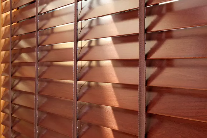 A window shaded by beautiful faux-wood blinds.