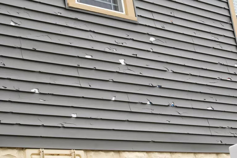 Vinyl siding on a home that has undergone damage and wear and tear that needs repair or replacement.