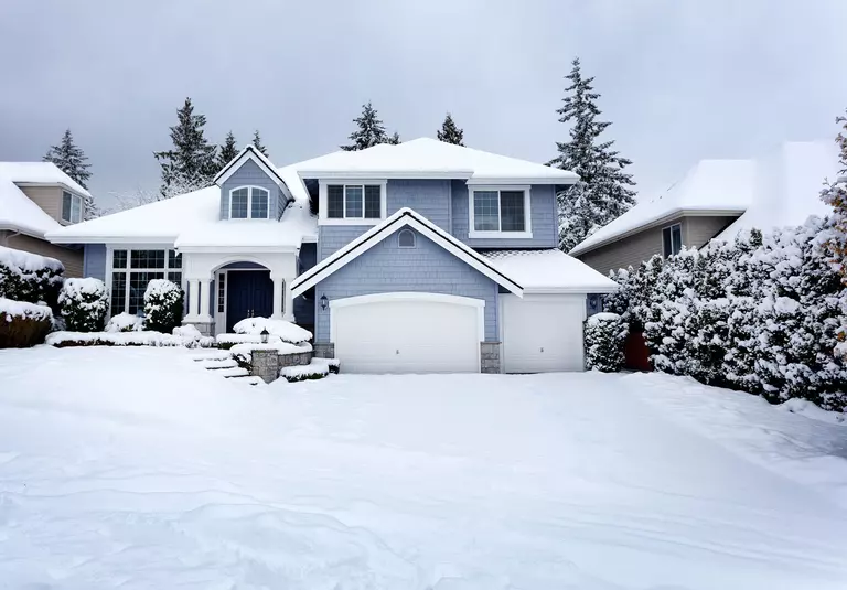 A blanket of snow covering a house and its yard and driveway.