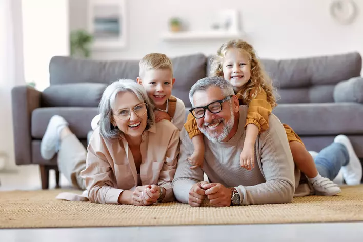 A married couple and their grandkids all smiling and having fun in the living room of
their age-in-place home.