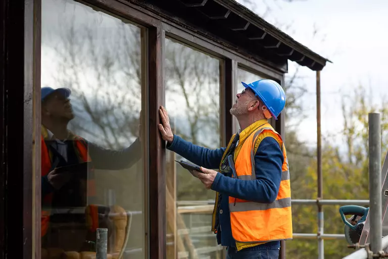 A worker checking the edges of full-wall windows.