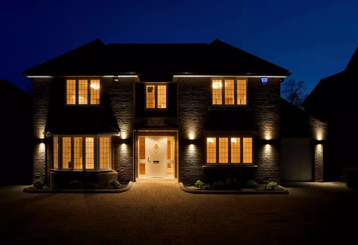 A beautiful home at night with lights illuminating the front of the house.