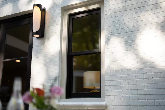 Black wood-clad double-hung windows on a modern white brick home