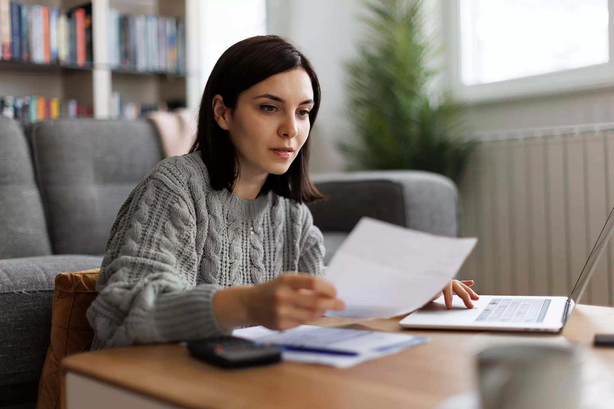 Woman sitting down at home reviewing financial documents.