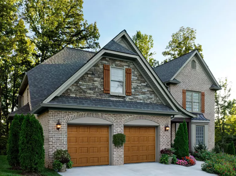 Home with brick exterior and two brown raised panel garage doors.