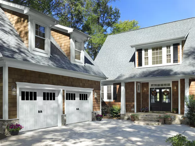 Home with a detached garage featuring white garage doors with vertical raised panels.