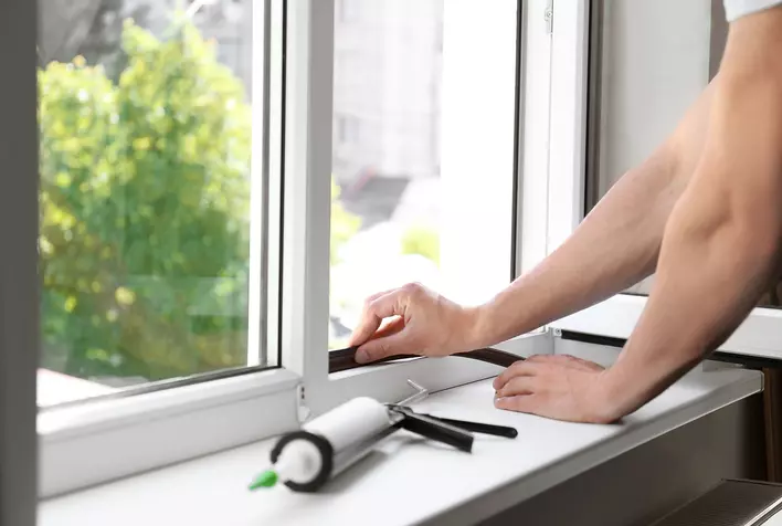 Installer replacing windows in a home with a caulking gun