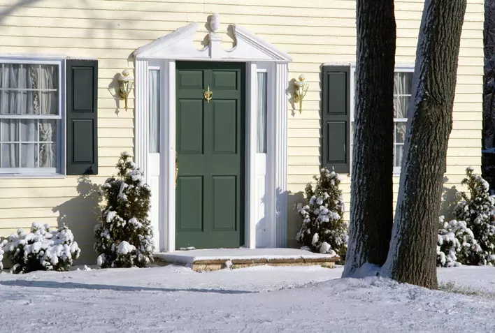 Front entry door of a home with a snow-covered entryway