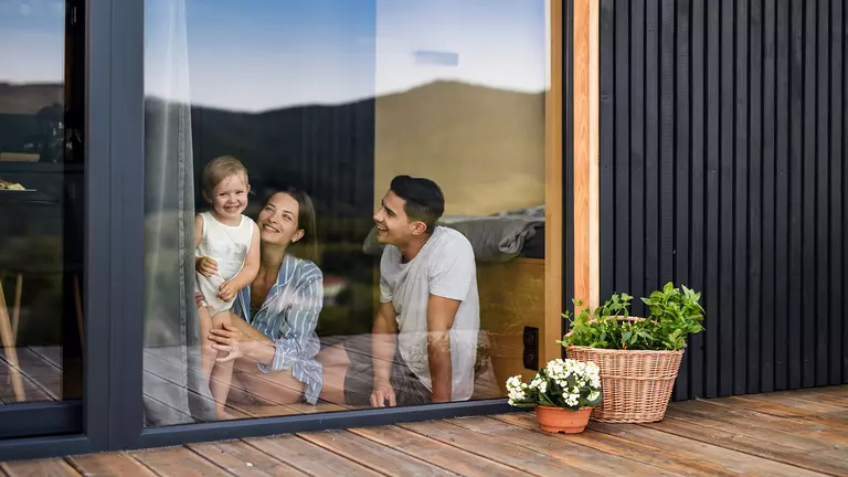 A couple with their child visible through the glass of a large window.
