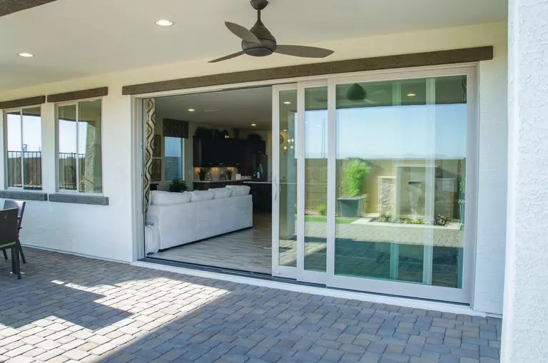 A large sliding patio door leading from the living room and kitchen of a home to the spacious back patio.
