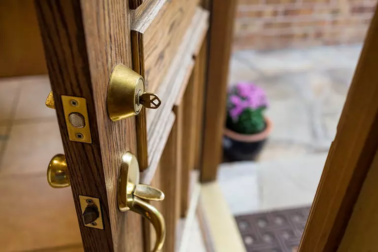 A wooden front door that has both a deadbolt lock and a lock on the handle.