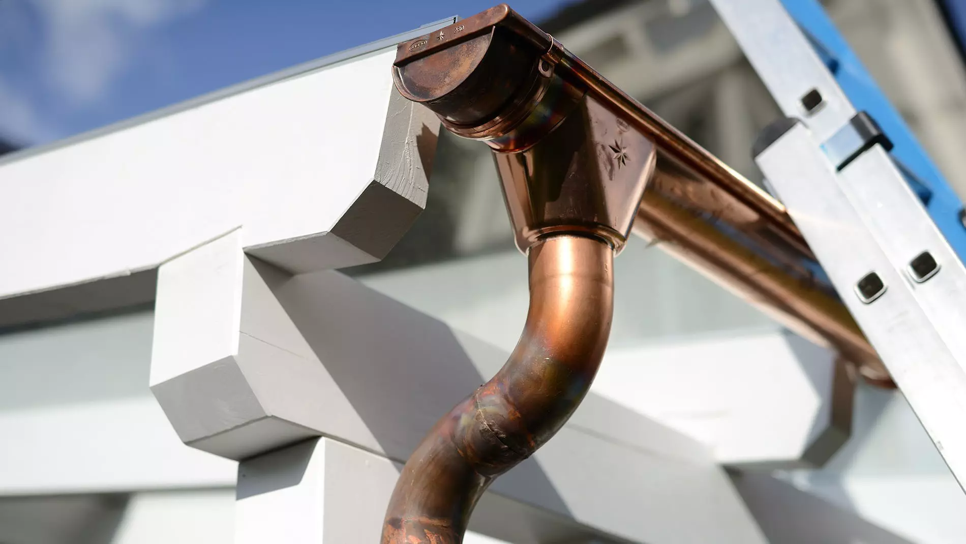 : A close-up view of a copper rain gutter on a house with the sky in the background