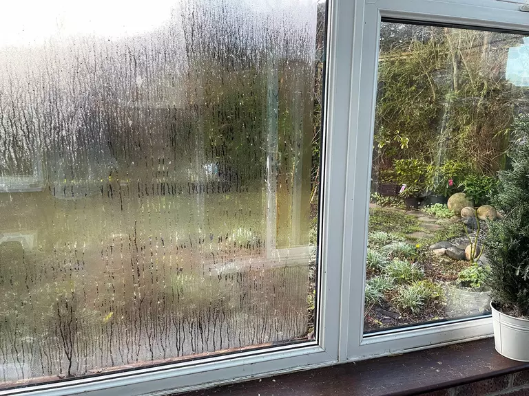 Close-up of a window with condensation between a pane of glass.