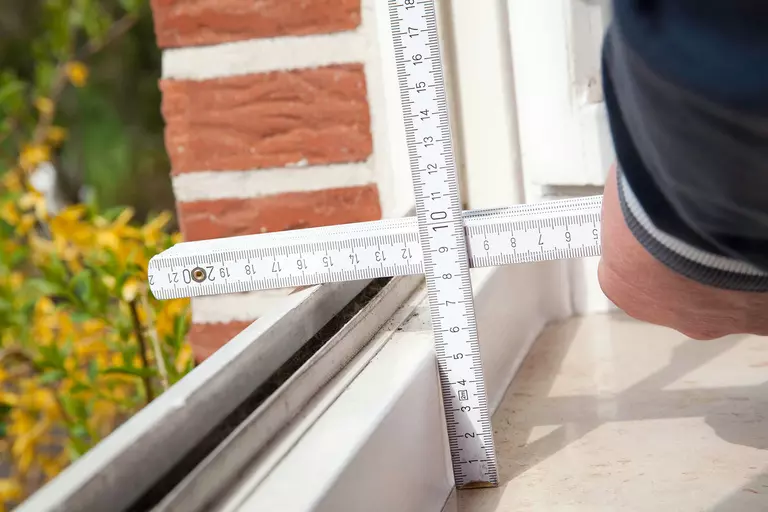 Man measuring the depth of a window with a square ruler.