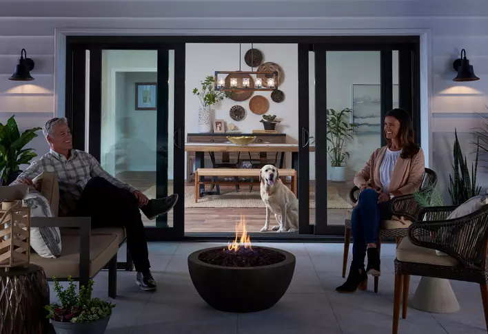 Couple enjoying a fire bowl in front of open sliding glass patio doors