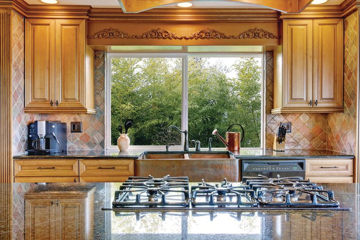Custom sliding windows within the kitchen of a home above the sink.