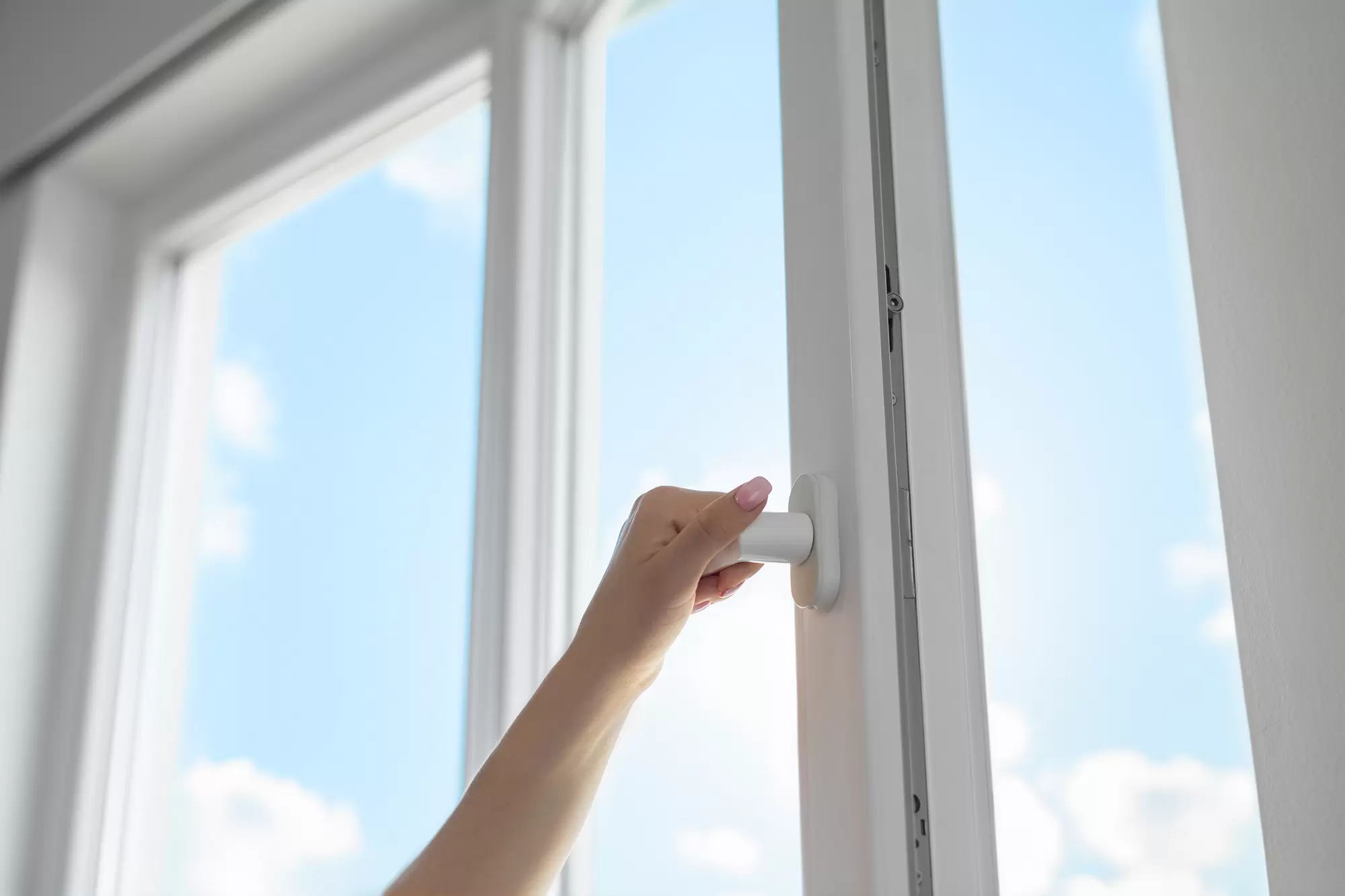 Woman operating a casement window handle.