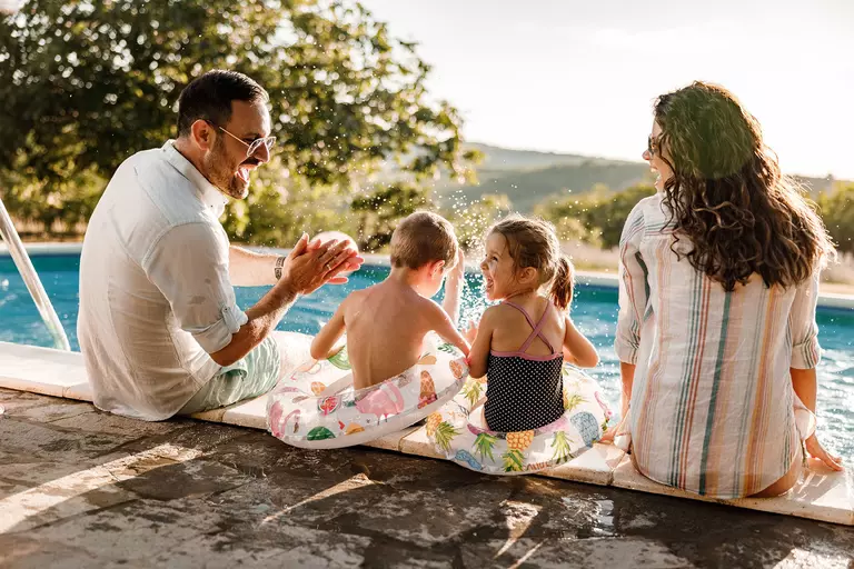 Happy family sitting poolside during the summer.