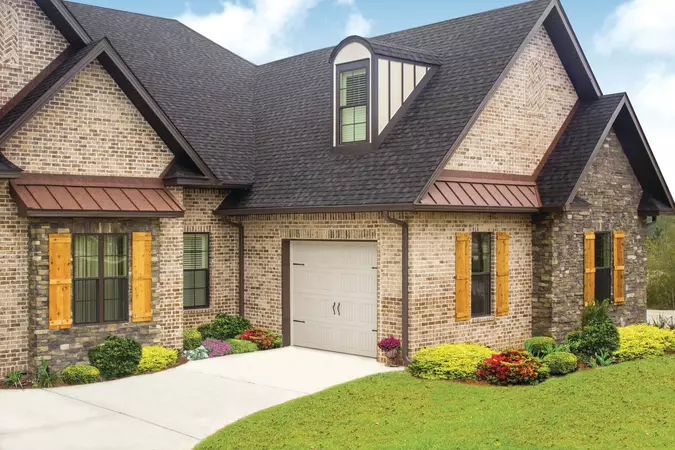 Almond short panel residential garage door installed on a brick home