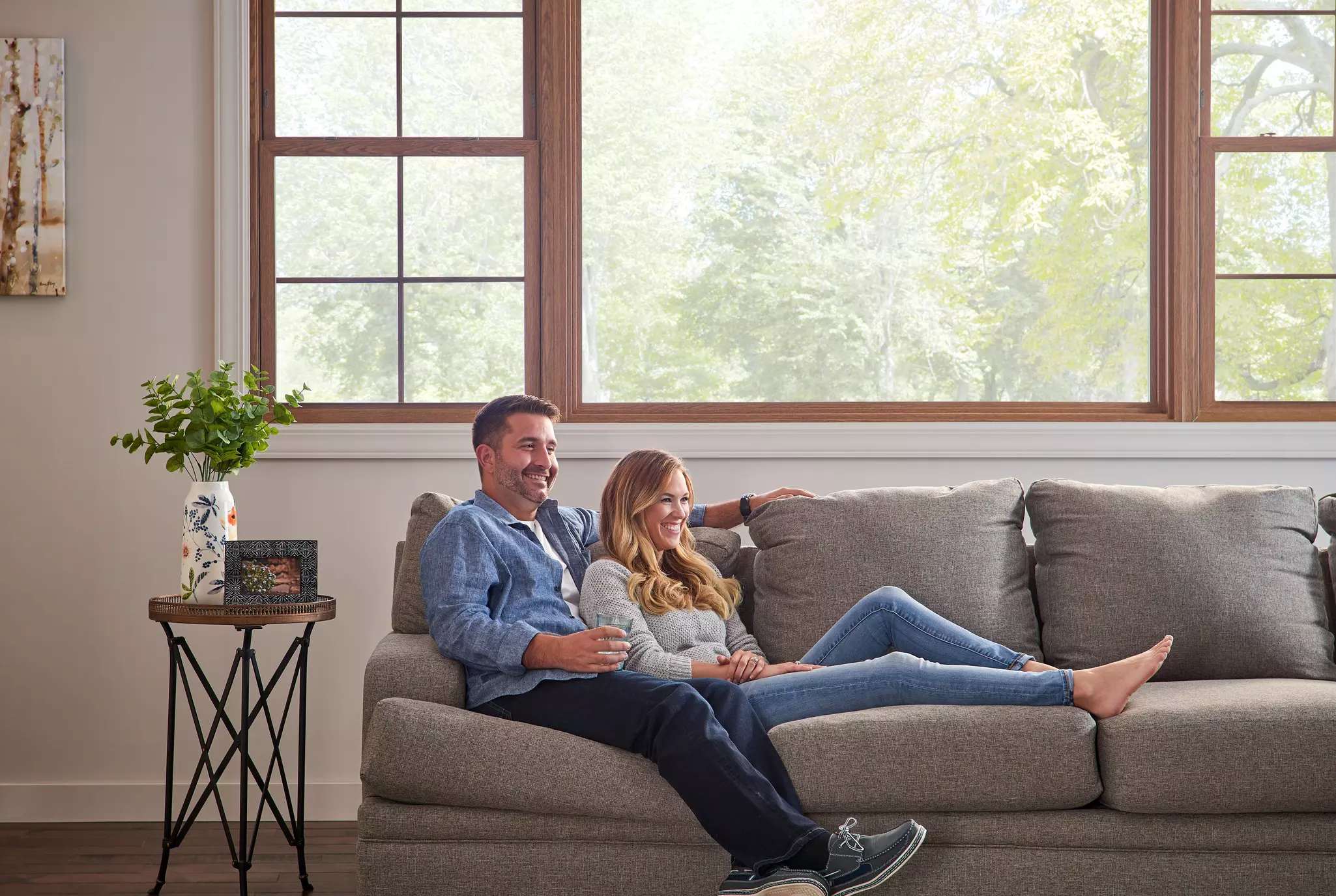 Couple relaxing in a quiet living room beside large energy-efficient windows.