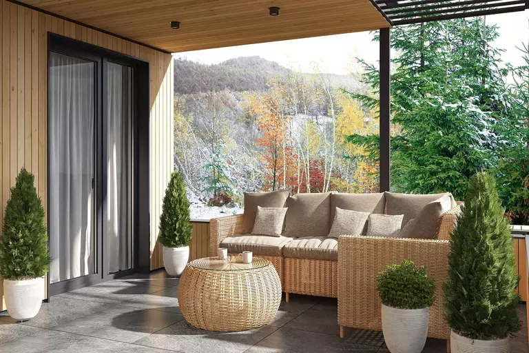 A sunny outdoor patio with a pair of sliding doors with curtains hanging inside.