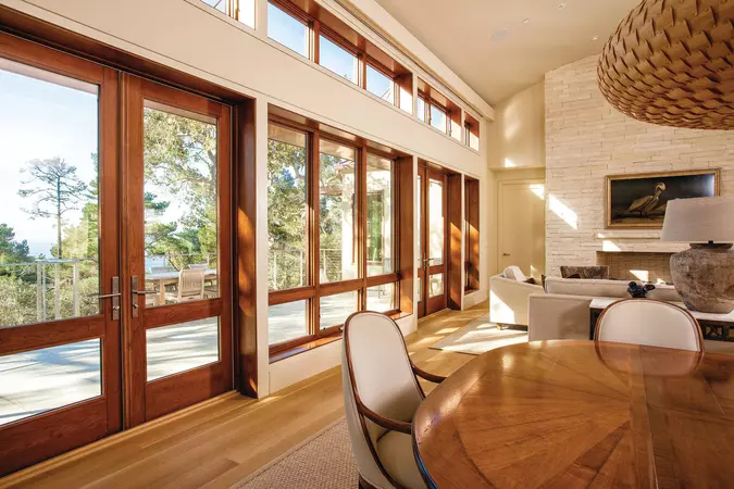 A living room with several windows and 2 wood interior hinged patio doors