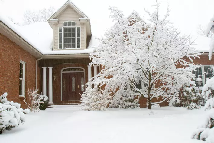 Brick house in the snow with a wooden exterior door