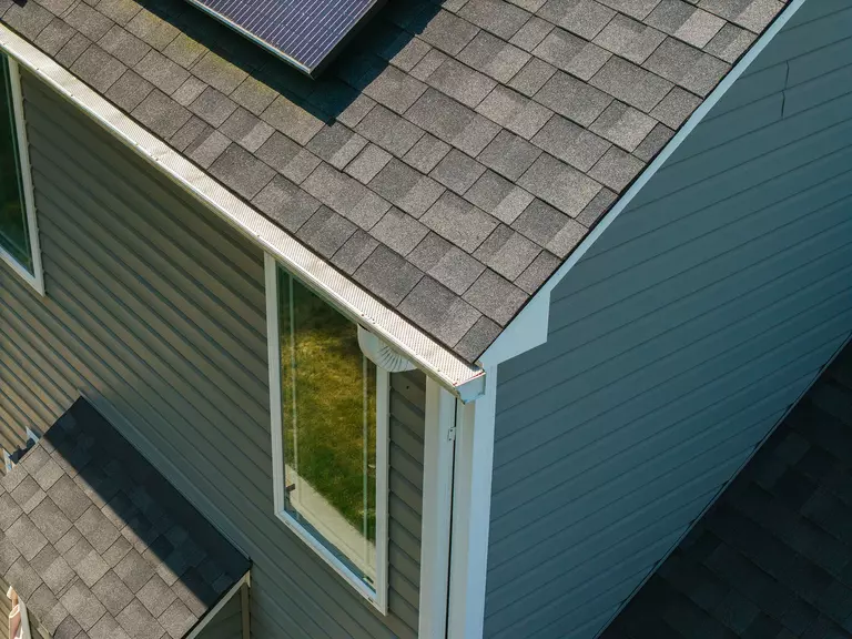 Roof of a home with gutter guard system attached.