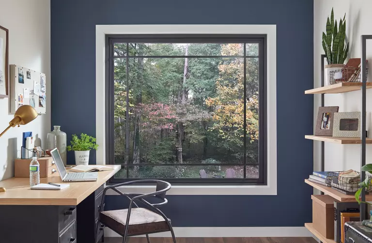A large picture window on a blue wall in an office space. Larger windows are generally less energy efficient than smaller ones.