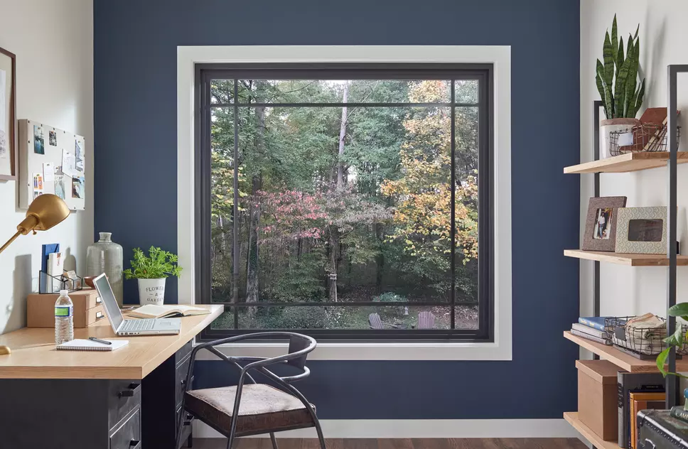 A modern style home office with a black picture window that has prairie grids