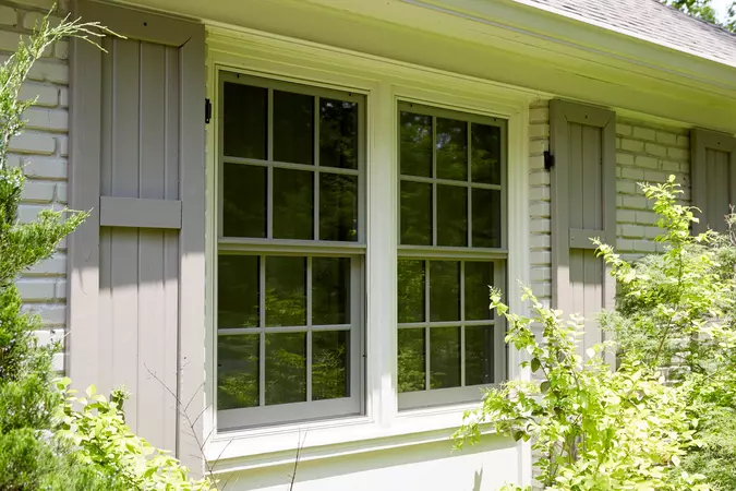 Full-screen wood-clad double-hung windows with gray shutters