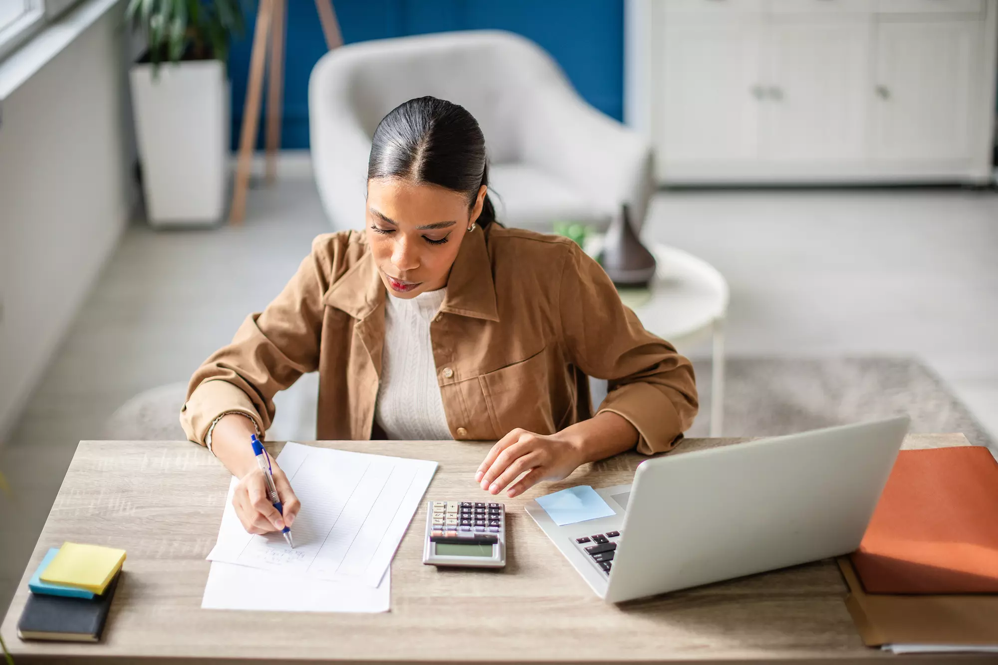 Woman reviewing financial documents in front of a laptop.