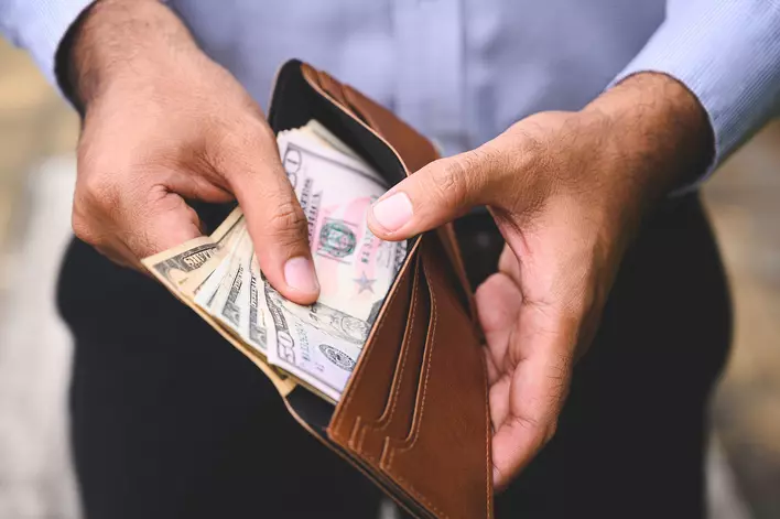 Close-up of a man counting the money spread of cash in a wallet.