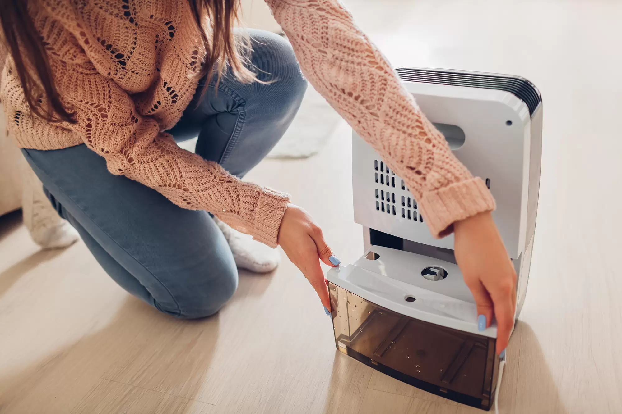 Woman adjusting a small dehumidifier.