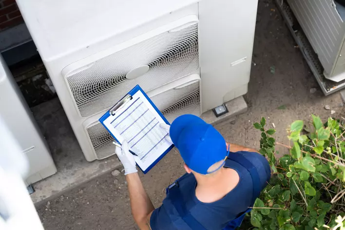 An HVAC contractor inspecting the HVAC system of a home to make sure it is running well and maintaining energy efficiency.