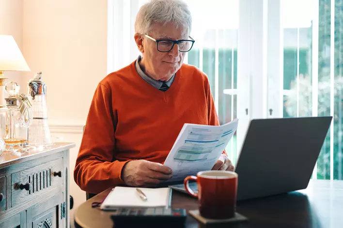 An older man looking through his utility bills for the month.
