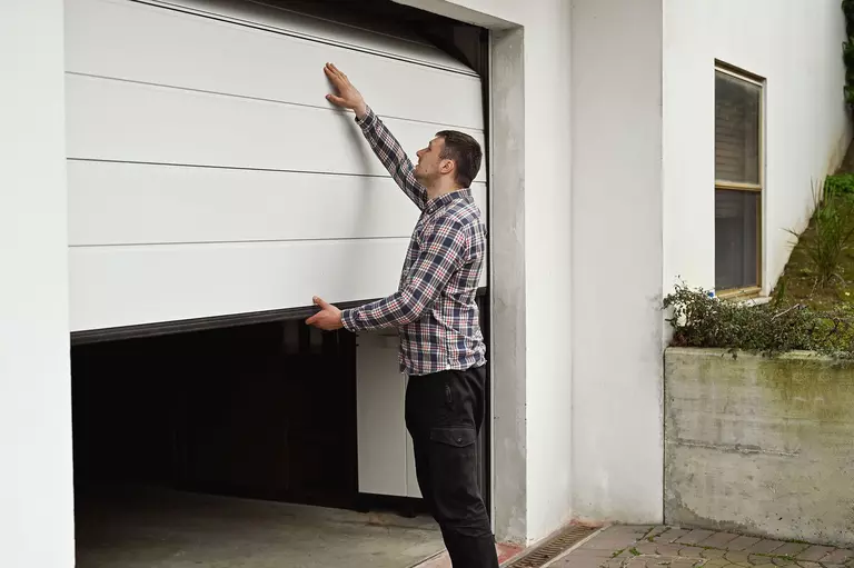 Man locking down the garage door of his home.