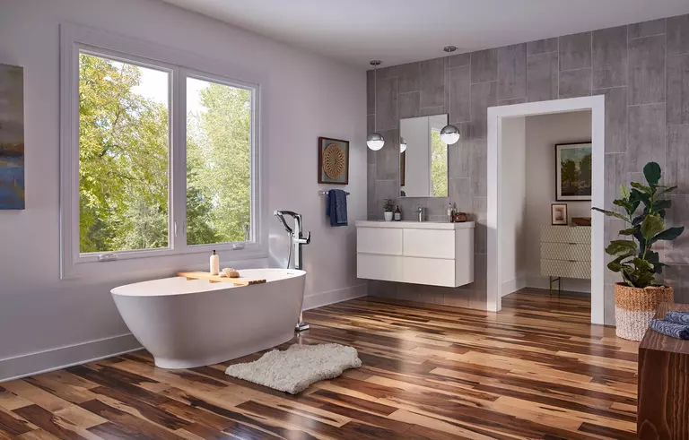A modern bathroom with a large white casement window over a freestanding tub.
