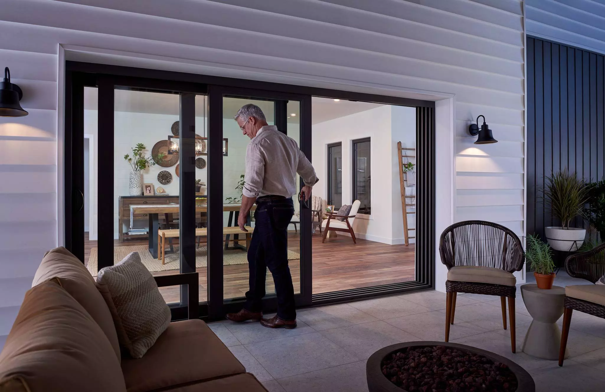 Man opening up multi-panel sliding patio door at night.
