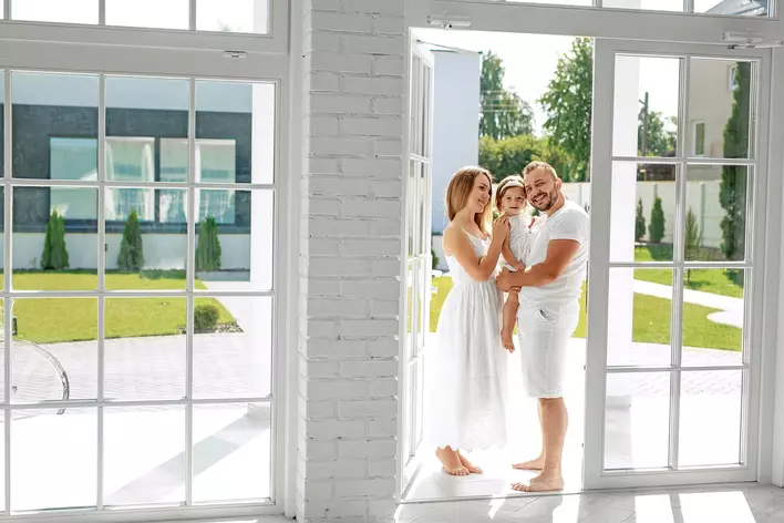 A young family in front of an  energy-efficient patio door leading out to a spacious yard.
