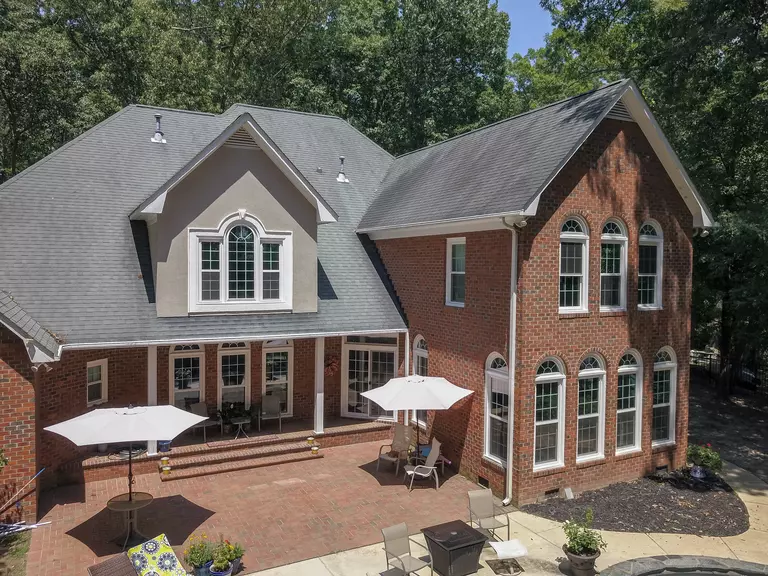 Two-story home’s back patio featuring white windows with arched tops.