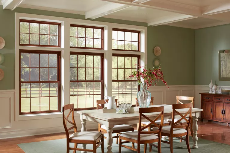 A dining room with three double-hung brown windows.