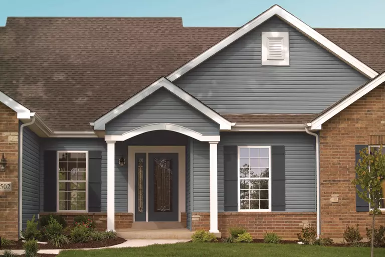 The front of a home with an exterior of blue vinyl siding and brick.