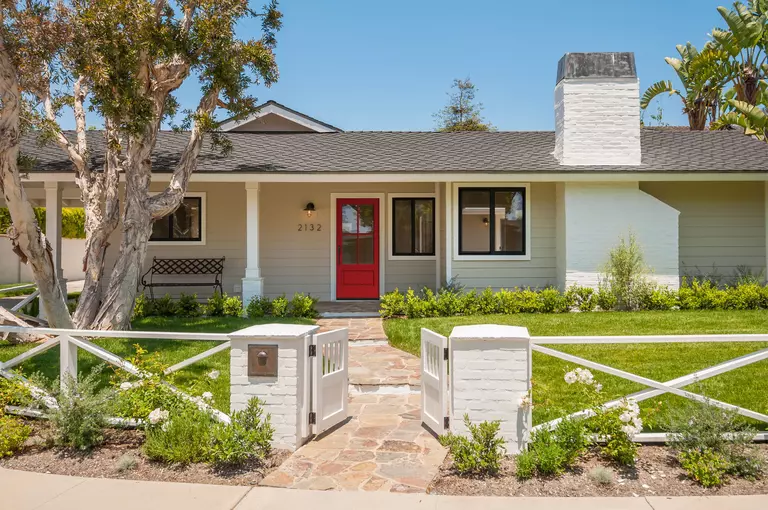 A beige siding home with a red entry door, large energy-efficient windows, and a large front yard.
