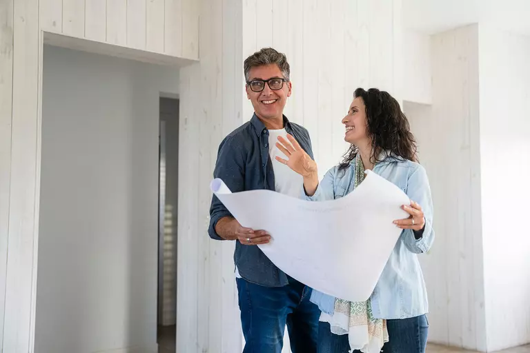 Man and woman in home happily looking at home improvement plans.
