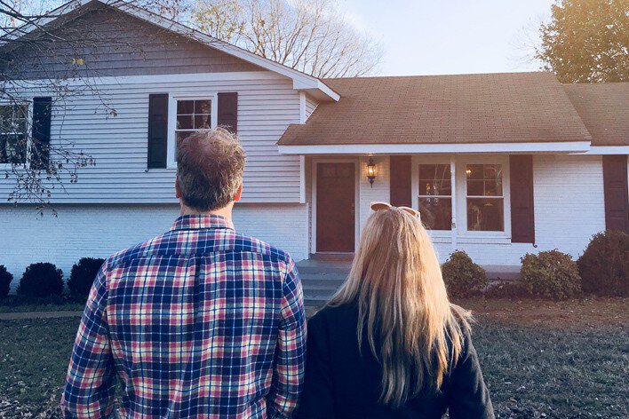 Man and woman looking at the exterior of a split-level home