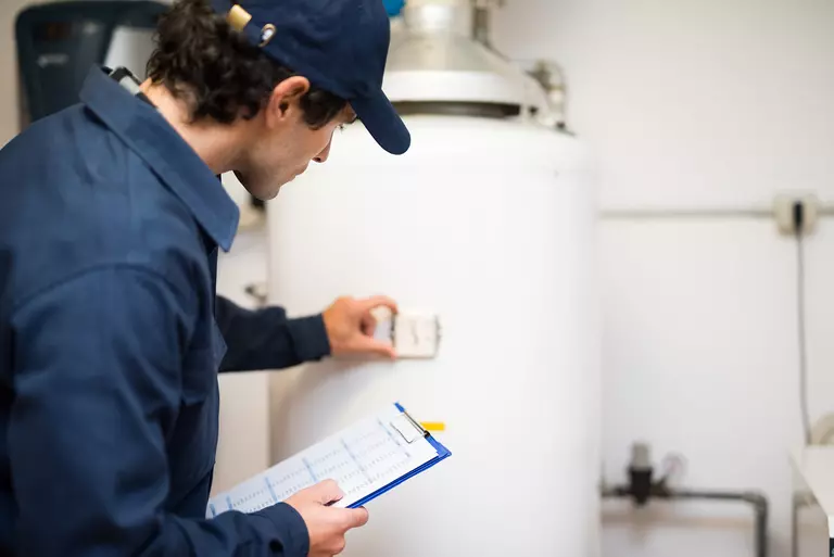 A contractor examining the water heater in the basement of a historic home.